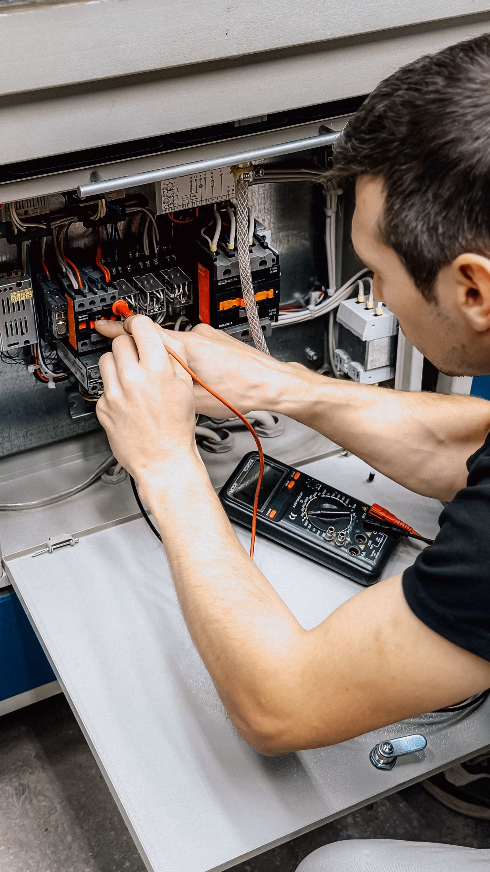 Elektrikář měří zapojení v otevřeném rozvaděči.